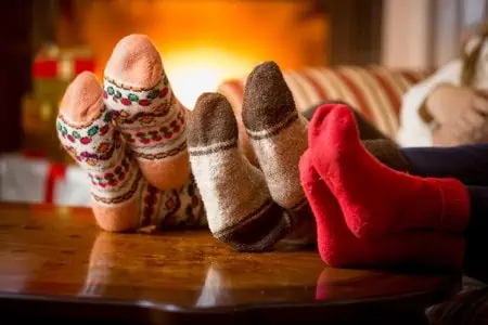 closeup photo of family feet in wool socks at fireplace