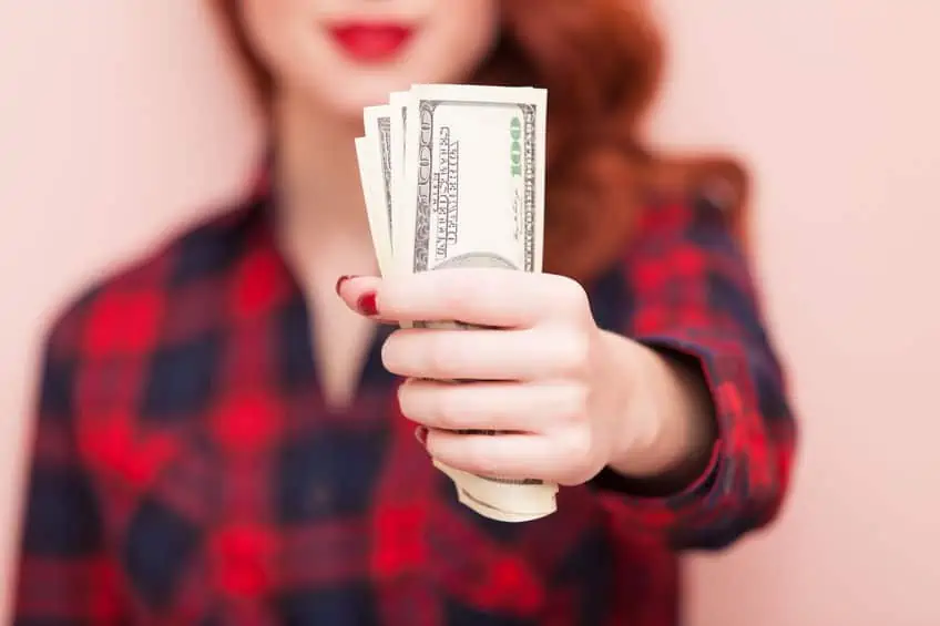 Woman holding money in her hands she earned from side hustles to make an income.