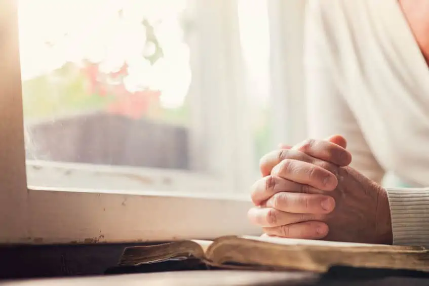 hands of a woman with bible praying