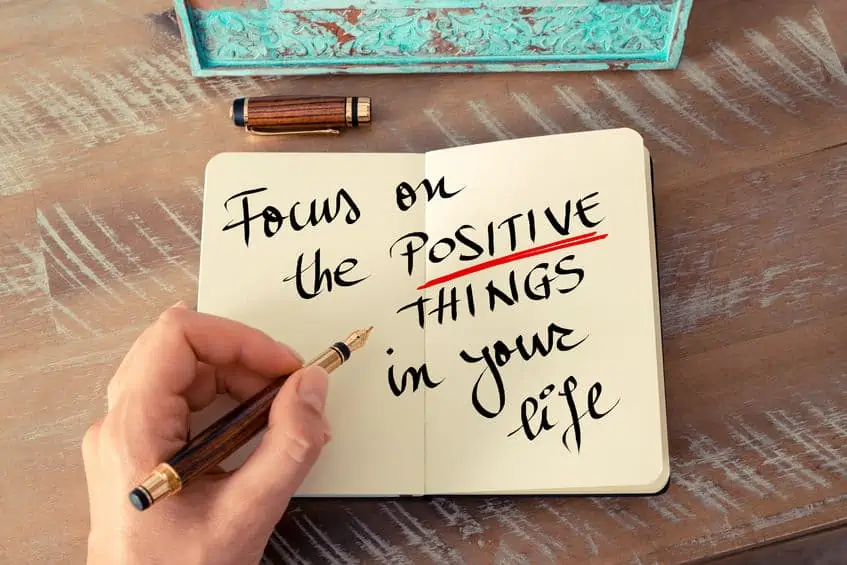 retro effect and toned image of a woman hand writing a note with a fountain pen on a notebook. handwritten text focus on the positive things in your life as business concept image