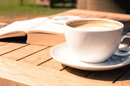 54109310 - coffee mug and a book on a wooden table