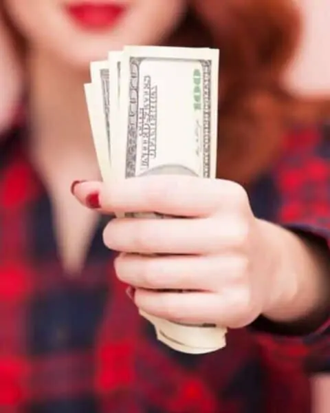 A woman holding a handful of cash and 100 bills.