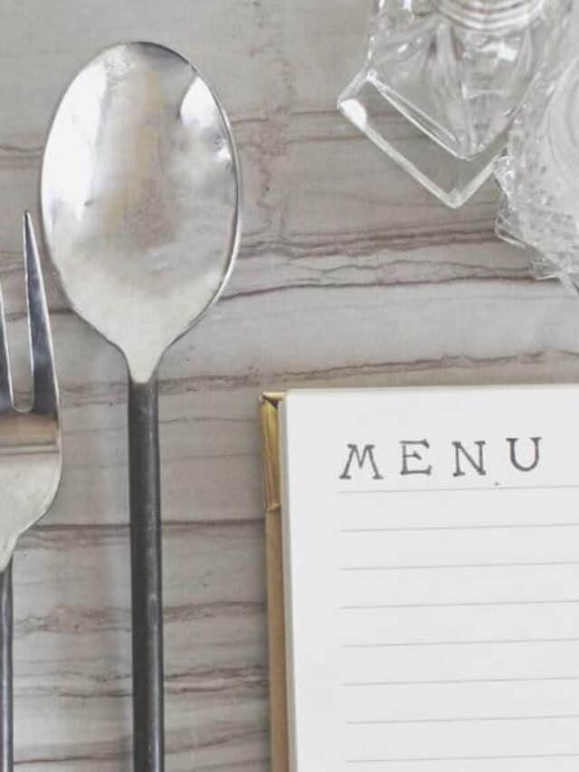 A fork and spoon next to a menu on the table.