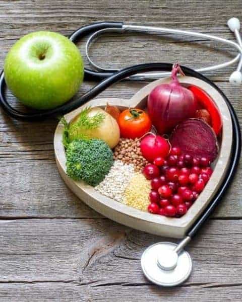 healthy food in a heart shaped bowl with a stethescope wrapped around it