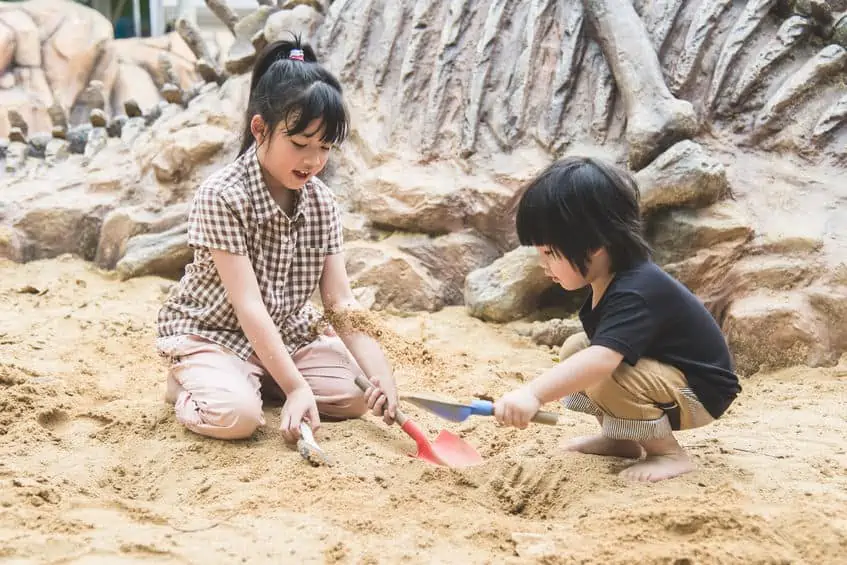 Children digging up dinosaur bones at museum. 