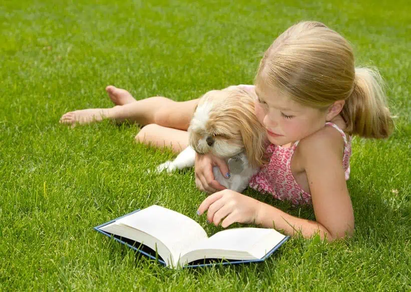 A little girl that is sitting in the grass