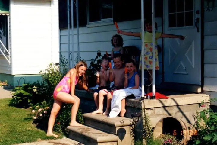 Group of children sitting on the front porch eating Popsicle 