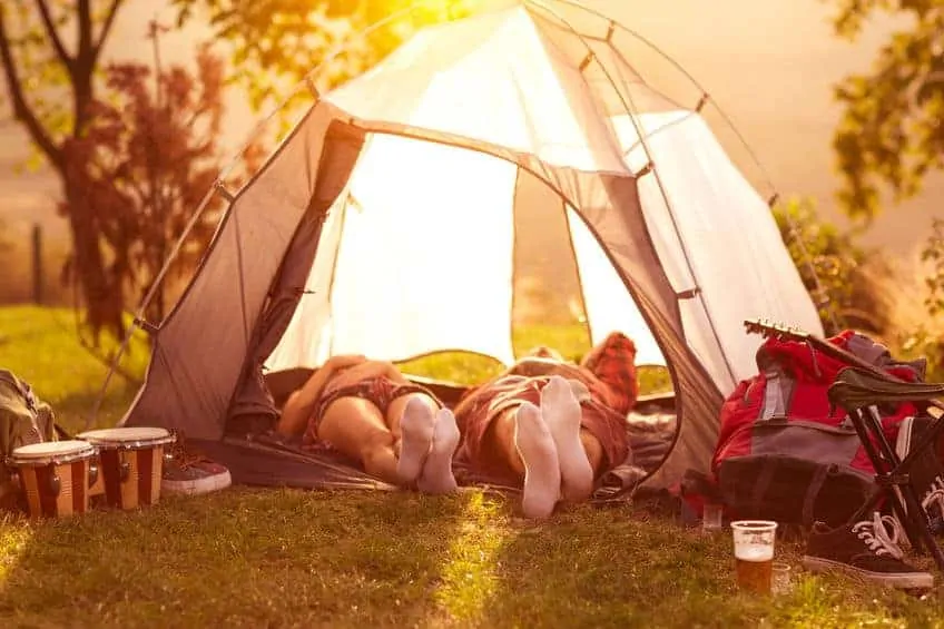 A couple laying down inside a tent with the flaps open. How to plan an awesome staycation for your family.