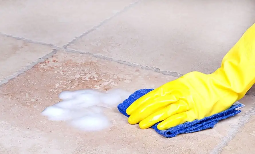 Scrubbing the dirty floor by hand with soap and water.