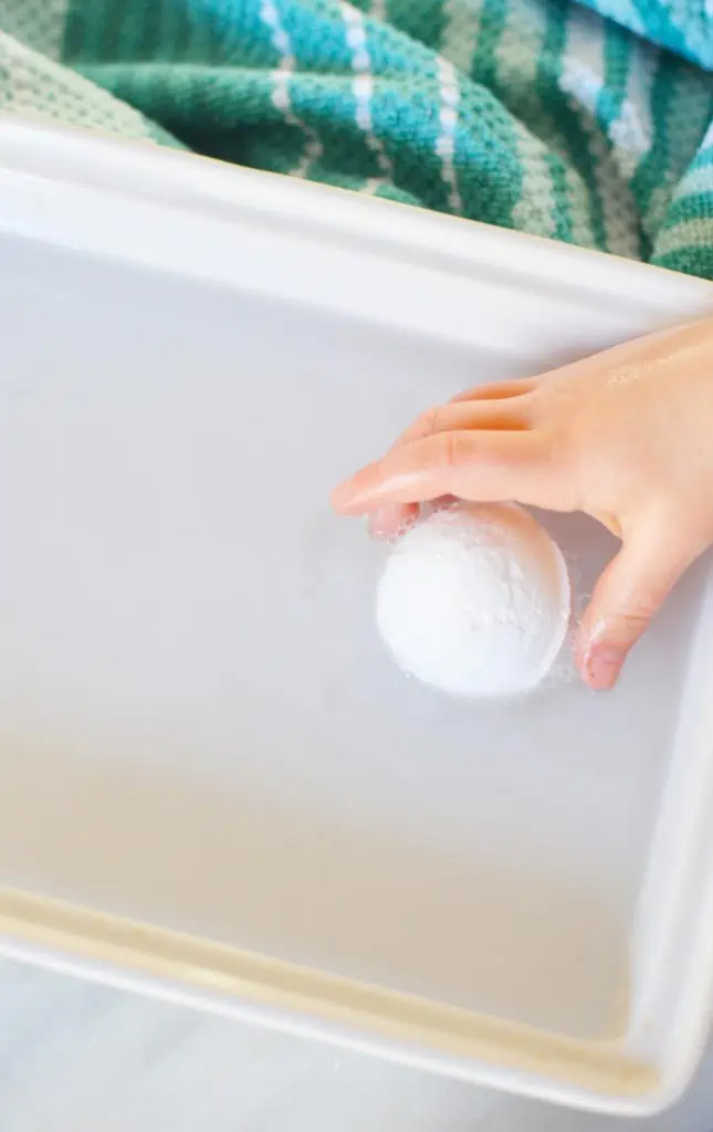 Child placing Calming Bath Fizzies in tub.