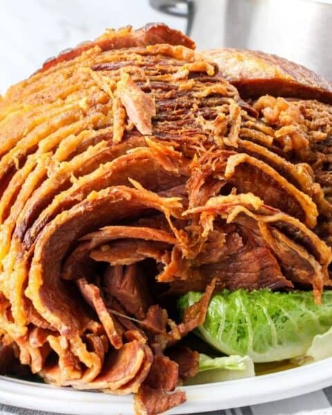 A cooked spiral ham next to a crock pot.