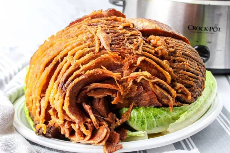 A cooked spiral ham next to a crock pot.