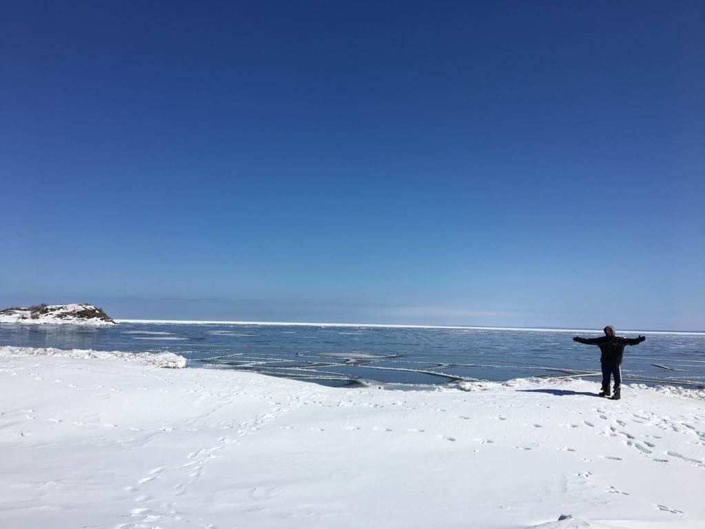 A man holding a snow board on a body of water
