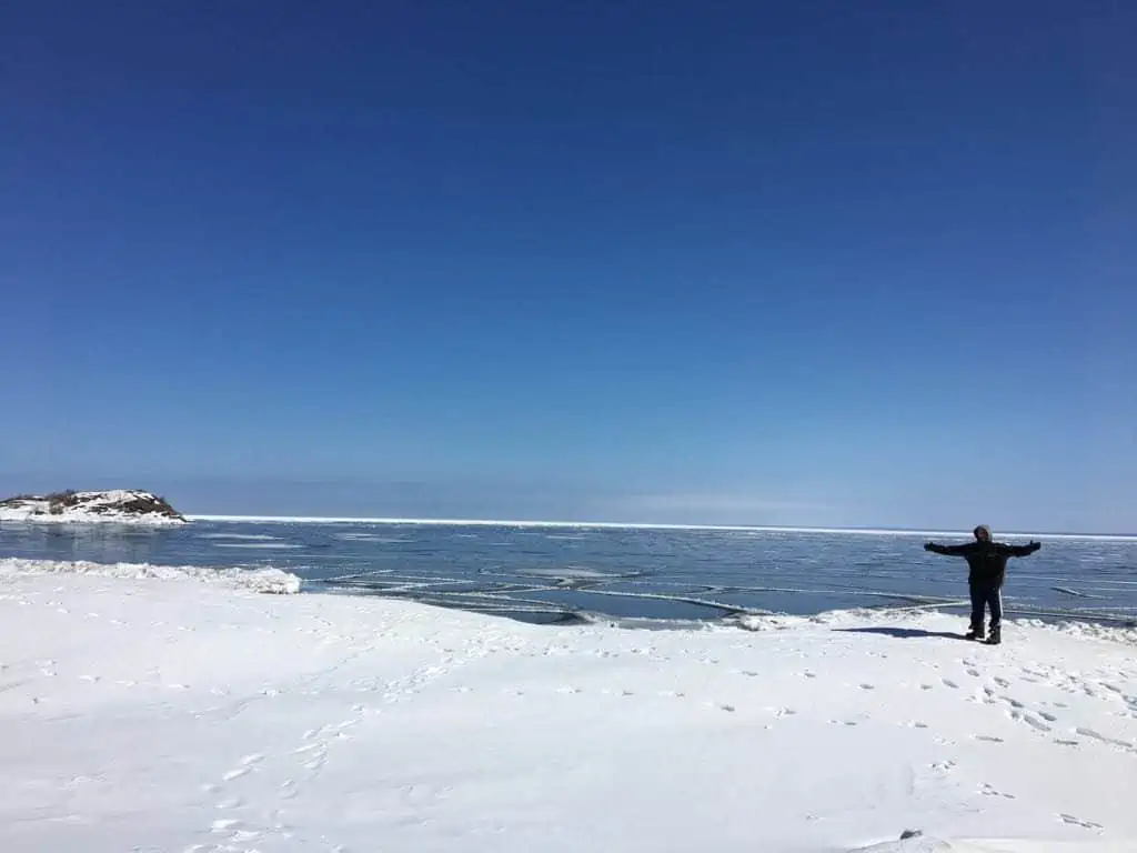 A man holding a snow board on a body of water