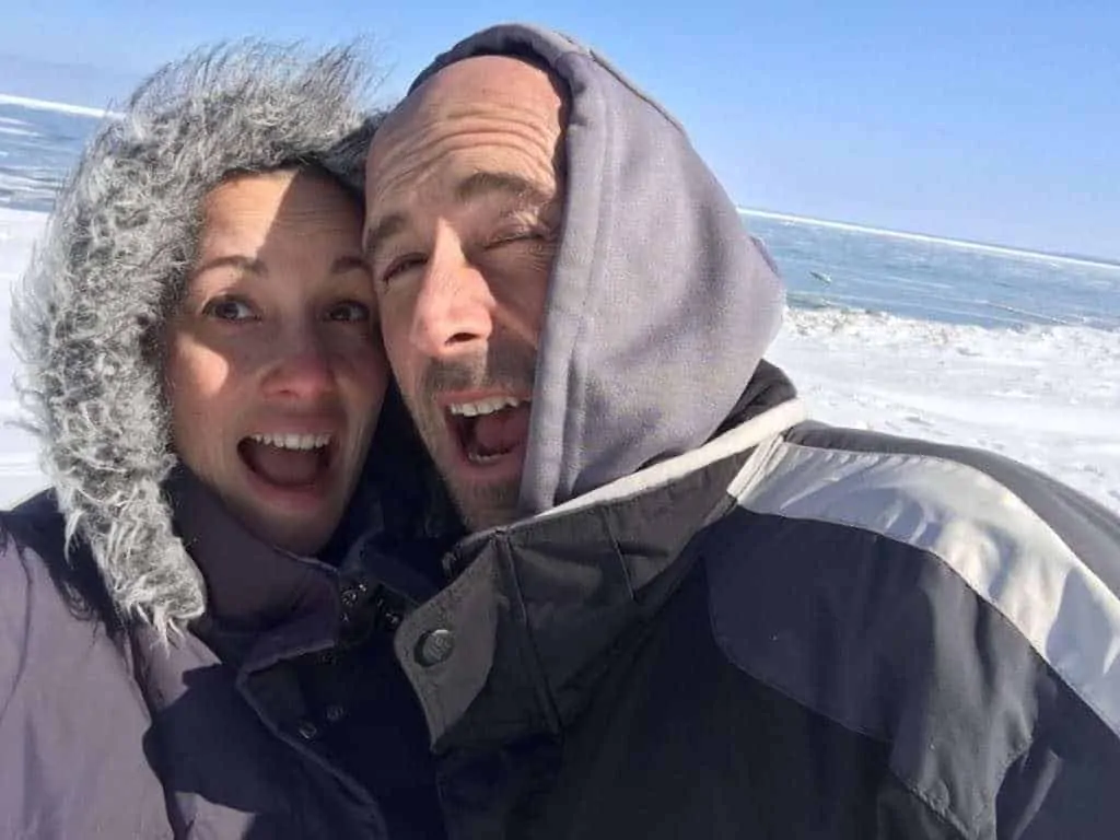 A couple posing and smiling on the beach in the middle of winter.