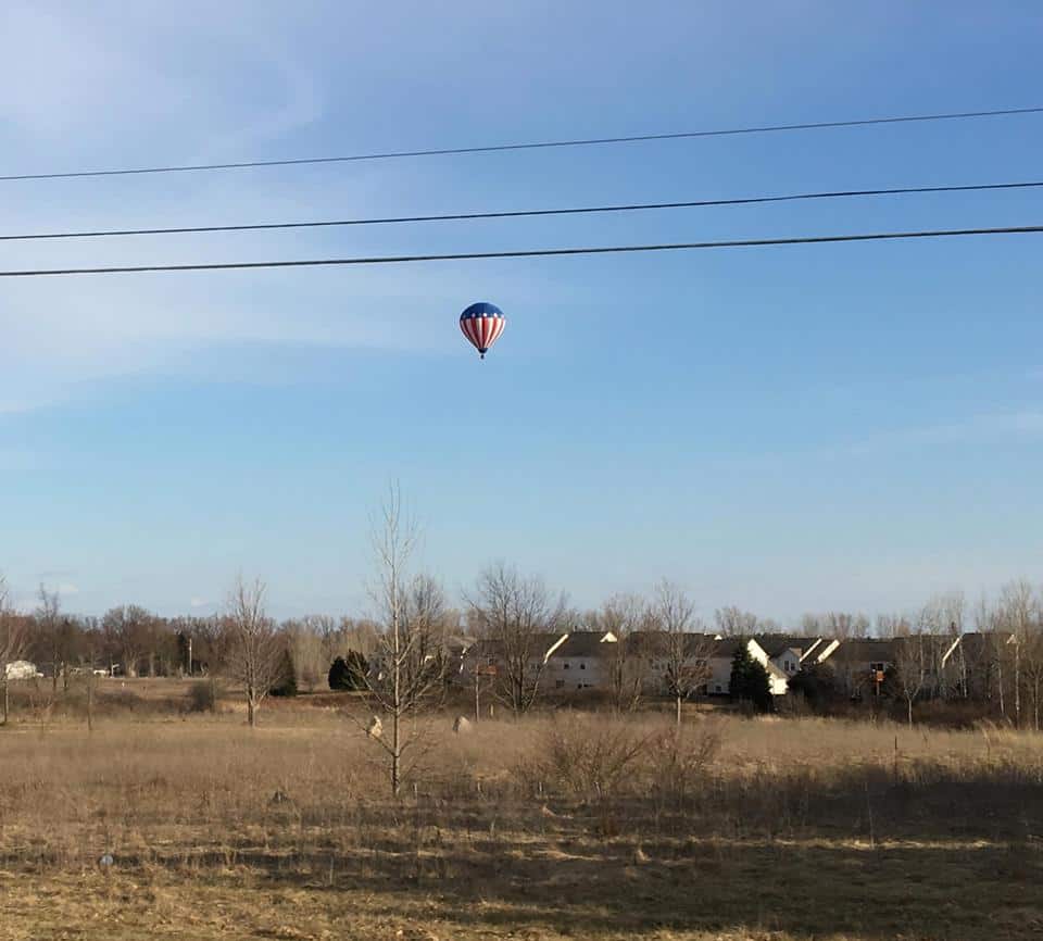 Hot air balloon in the sky over a quiet area in the country.