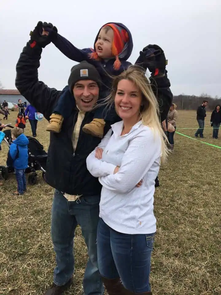 A group of people standing in the grass smiling and happy.