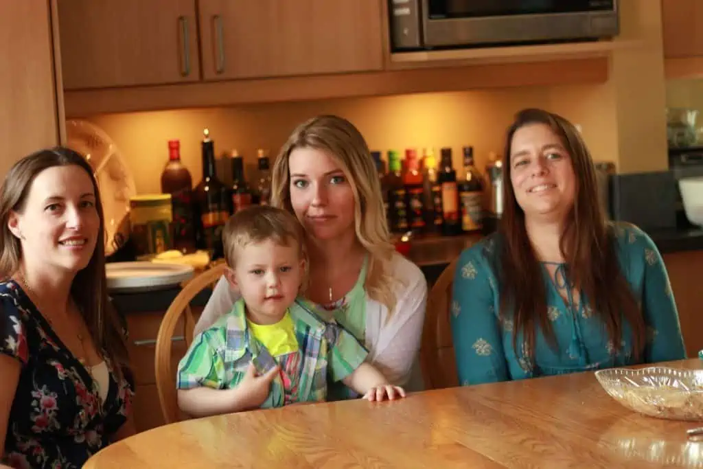 A small group of girls and a little boy sitting together at the kitchen table.