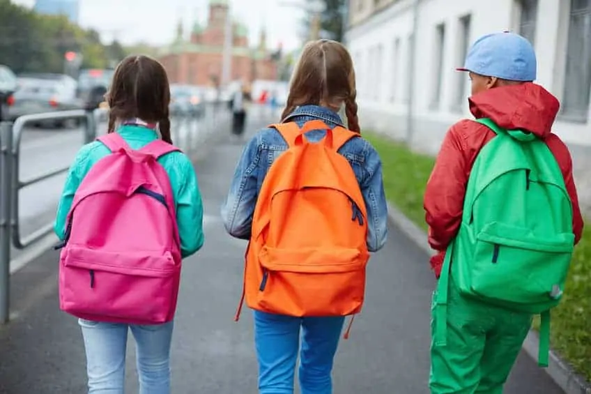 A group of  children walking down the street as they head to school.