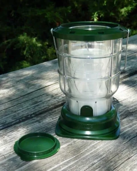 Coleman lantern sitting on a wooden picnic table