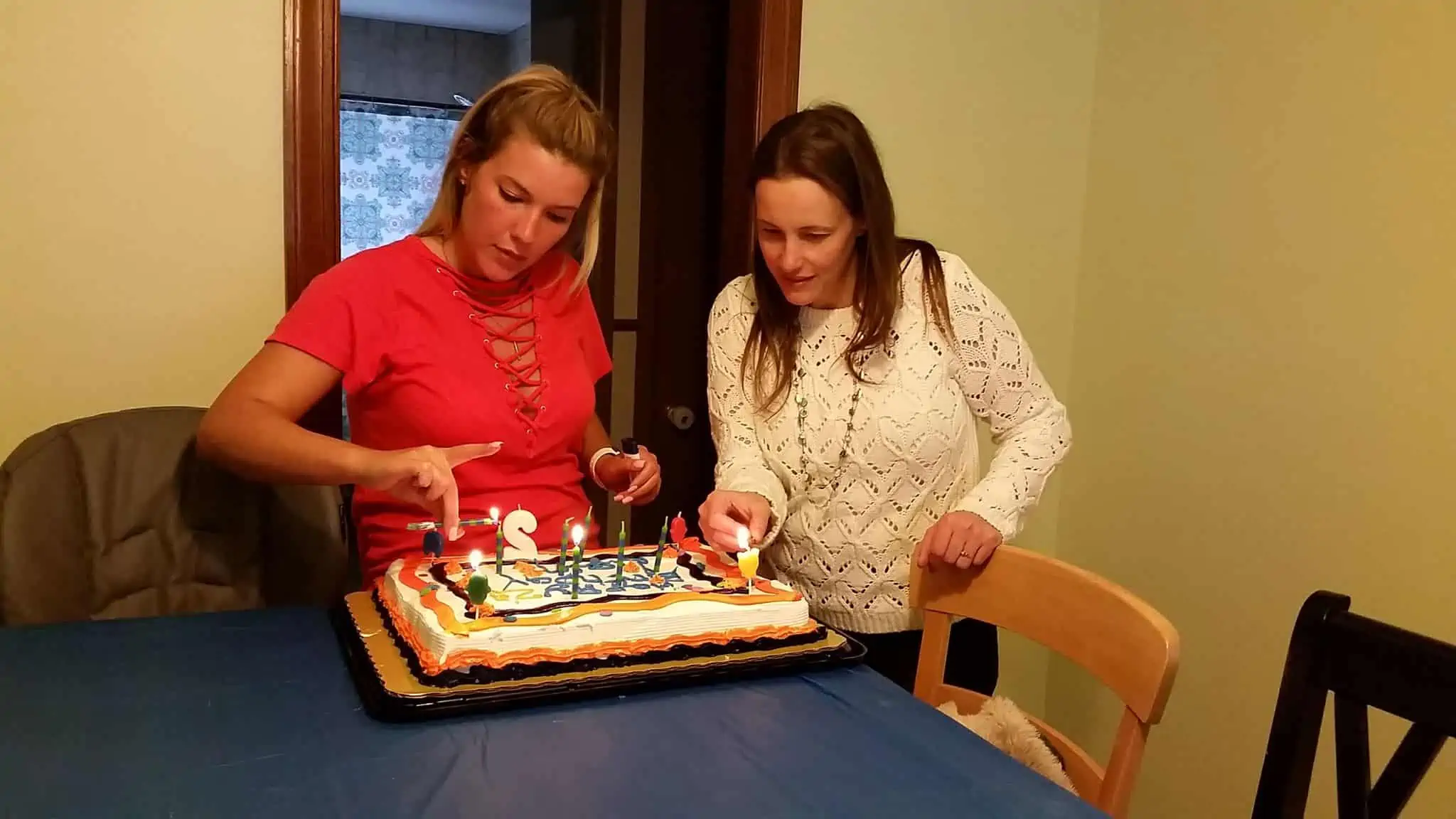 A small group of women surrounding a birthday cake.