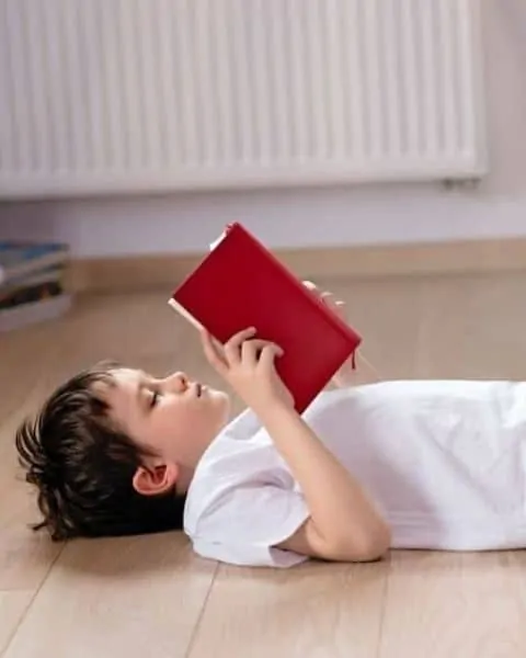 boy reading a book while laying on the ground