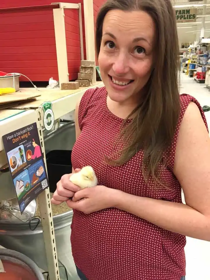 A woman holding a baby chick in her hands.