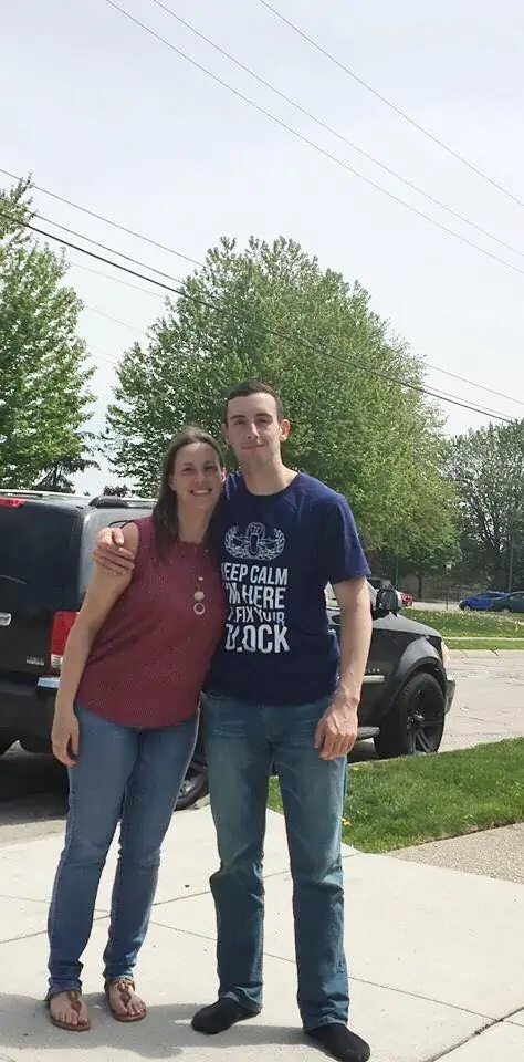 A man and a woman standing in a parking lot and embracing with joy.