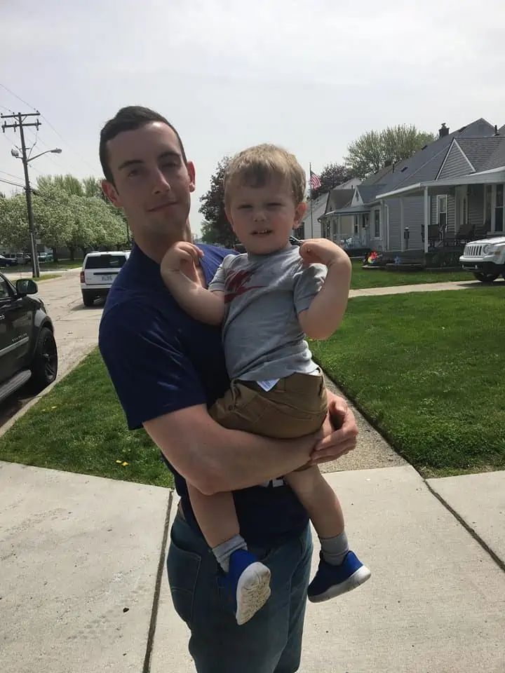 A small child in the arms of a man, smiling at the camera.