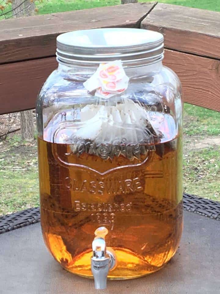 A giant jar of sweet tea sitting outside.