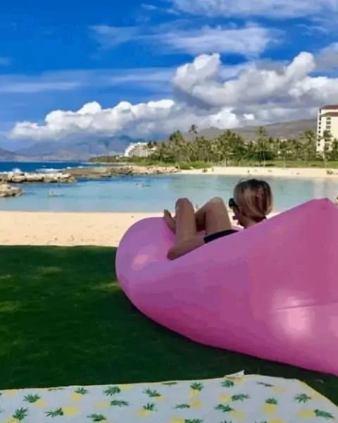 a woman sitting on a pink air lounger at the lake