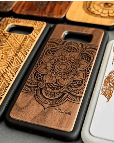 several wooden phone cases that are engraves with designs