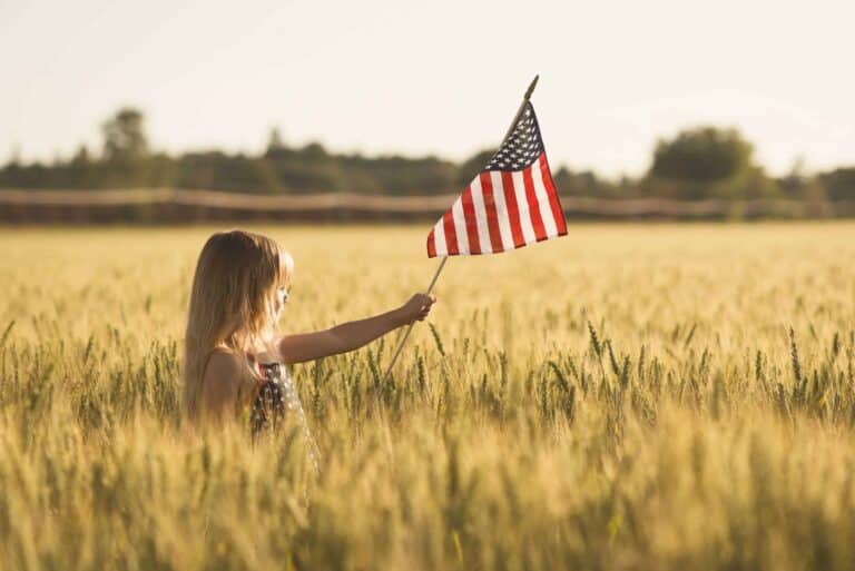 A little girl holding a small flag of the USA.