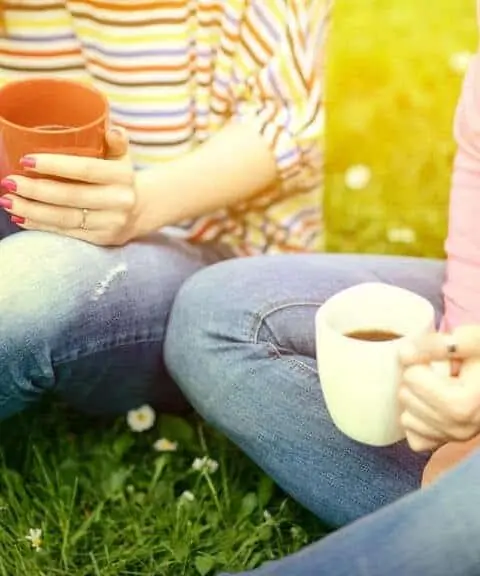 young women drinking coffee at park and enjoying summer day