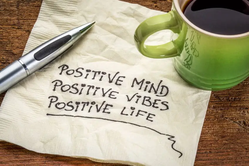 Morning coffee on top of napkin that reads, \"Positive mind, positive vibes, positive life.\"