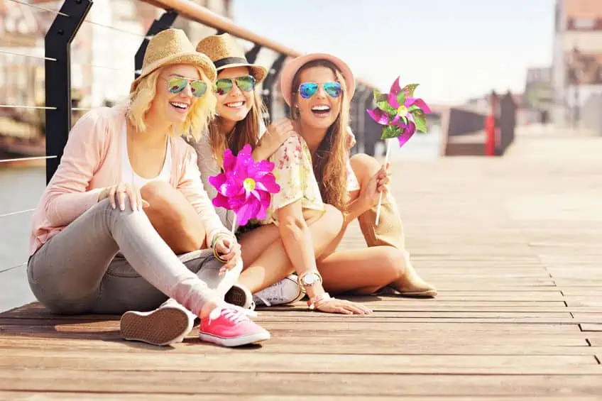 A group of women who are sitting on a boardwalk, happy and being social.