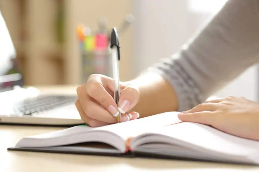Woman writing thoughts and personal feelings in notebook.