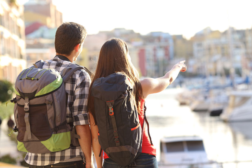 A couple holding hands and backpacking.