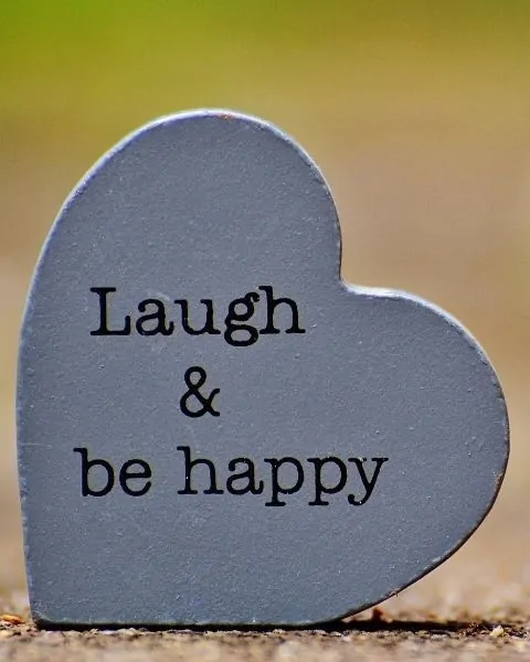 a heart shaped wooden plaque that says Laugh & Be Happy