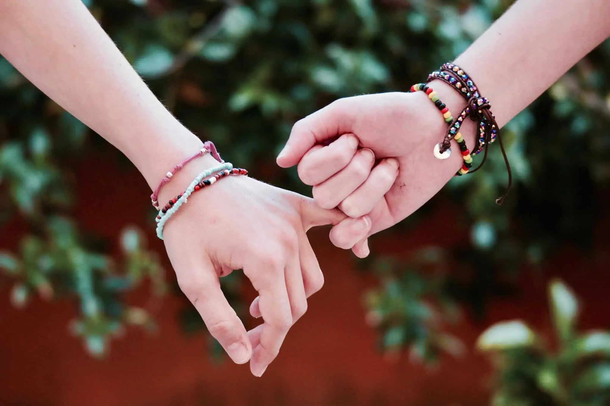 Two people interlocking fingers together in encouragement and kindness.