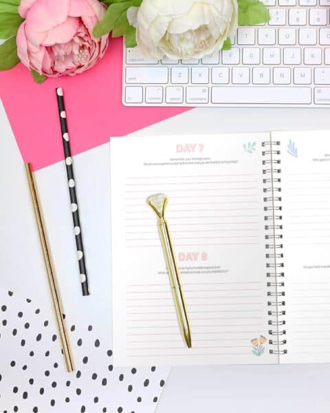 A desk overview with keyboard, flowers, and pens.