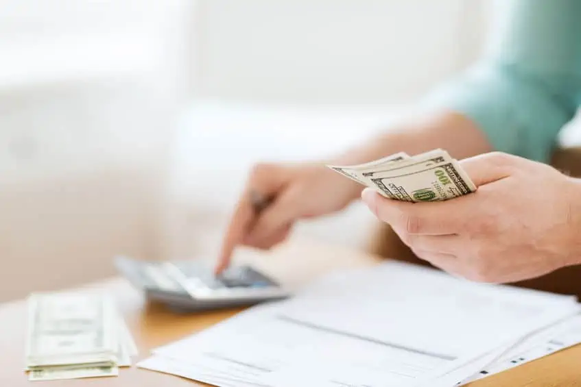 Woman doing a personal budget and paying bills with cash in hand.