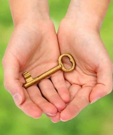 A woman holding a gold key in her palms.