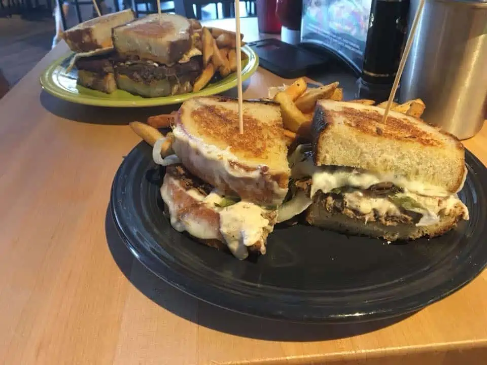 A sandwich cut in half on a plate, with Hotel Breakers and Menu