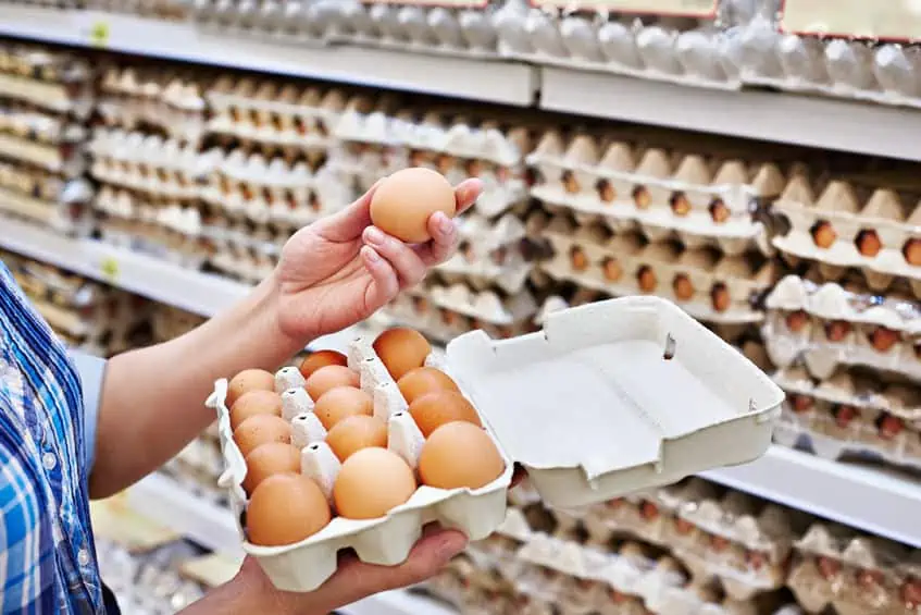 Woman examining eggs in the grocery store.