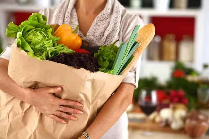 A woman holding a bag of healthy groceries in her arms.
