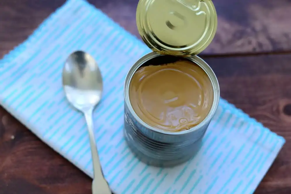 A cup of coffee sitting on top of a wooden table, with Caramel and Condensed milk