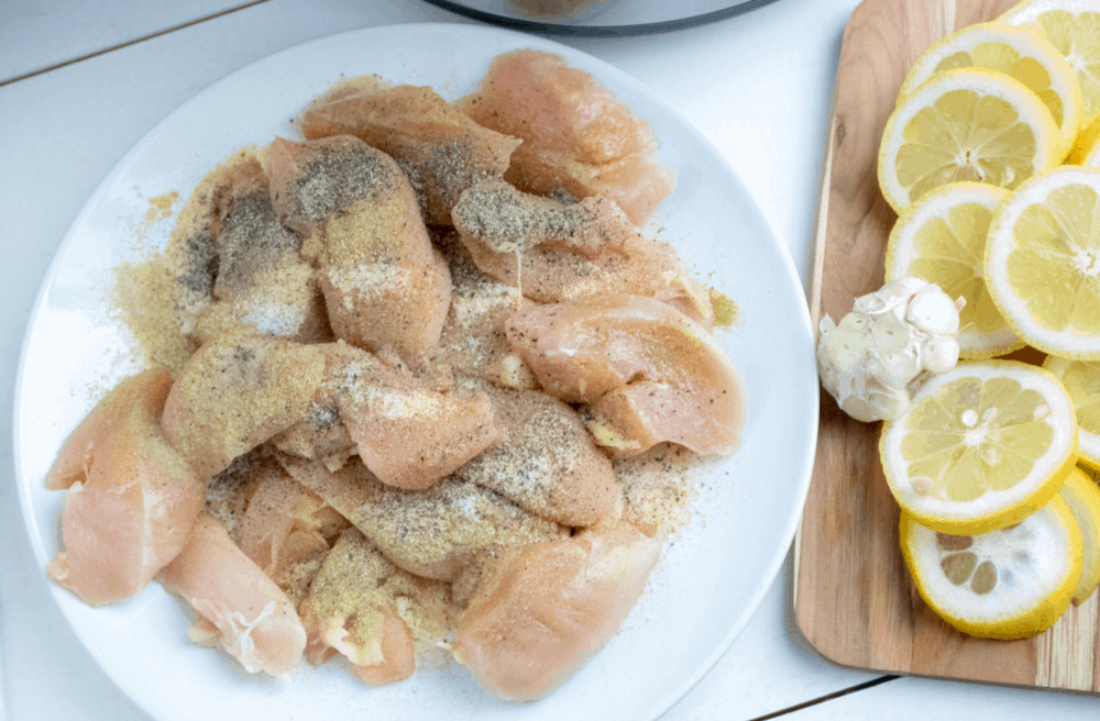 Raw chicken with seasonings and lemon.