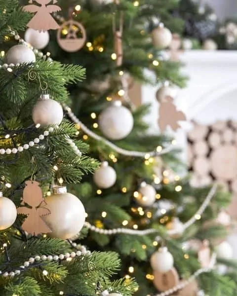 Christmas tree decorated in white lights and bulbs with beaded garland