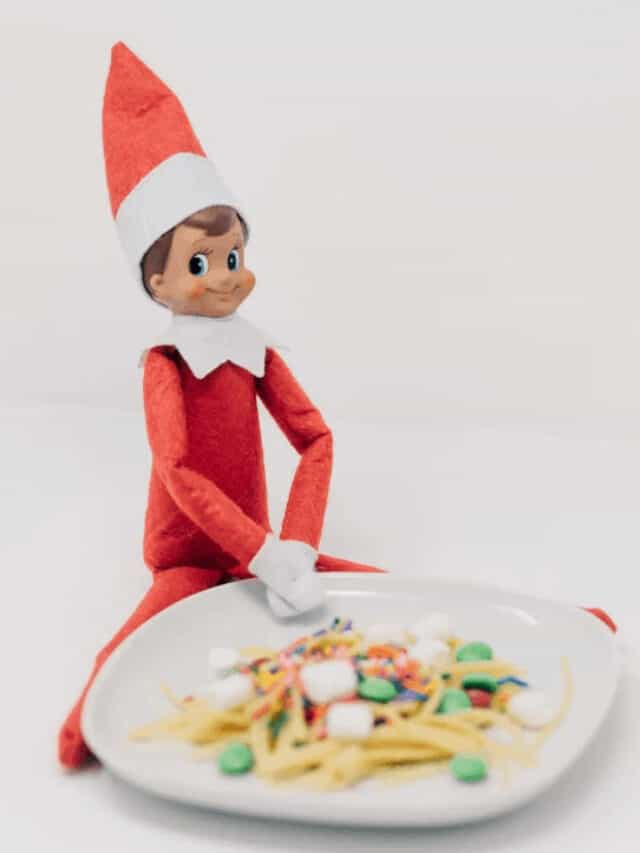 An elf on the shelf sitting next to a white plate filled with silly foods.